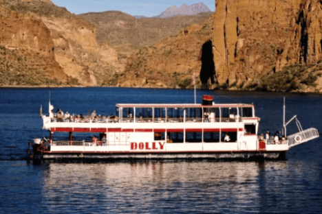Boat named Dolly on a lake with rocky hills in the background.