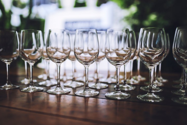 Rows of empty wine glasses on a wooden table with soft focus background.