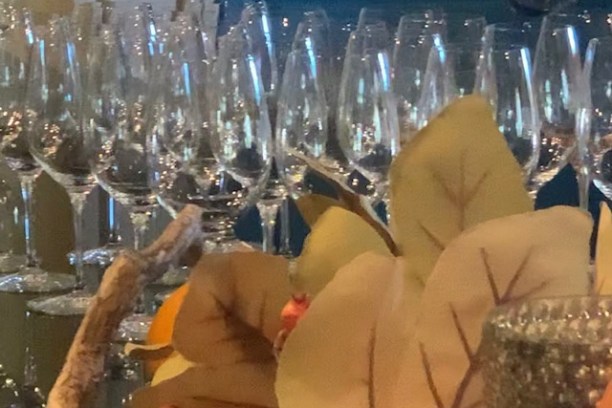Rows of empty wine glasses behind autumn leaves and decor.