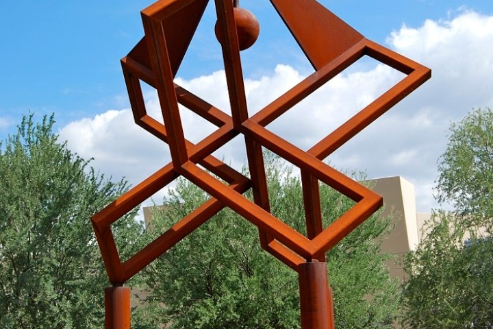 Abstract metal sculpture with geometric shapes in a desert landscape.